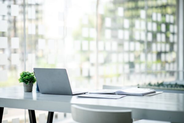 A modern office workspace with a laptop, open book, and small plant on a table.