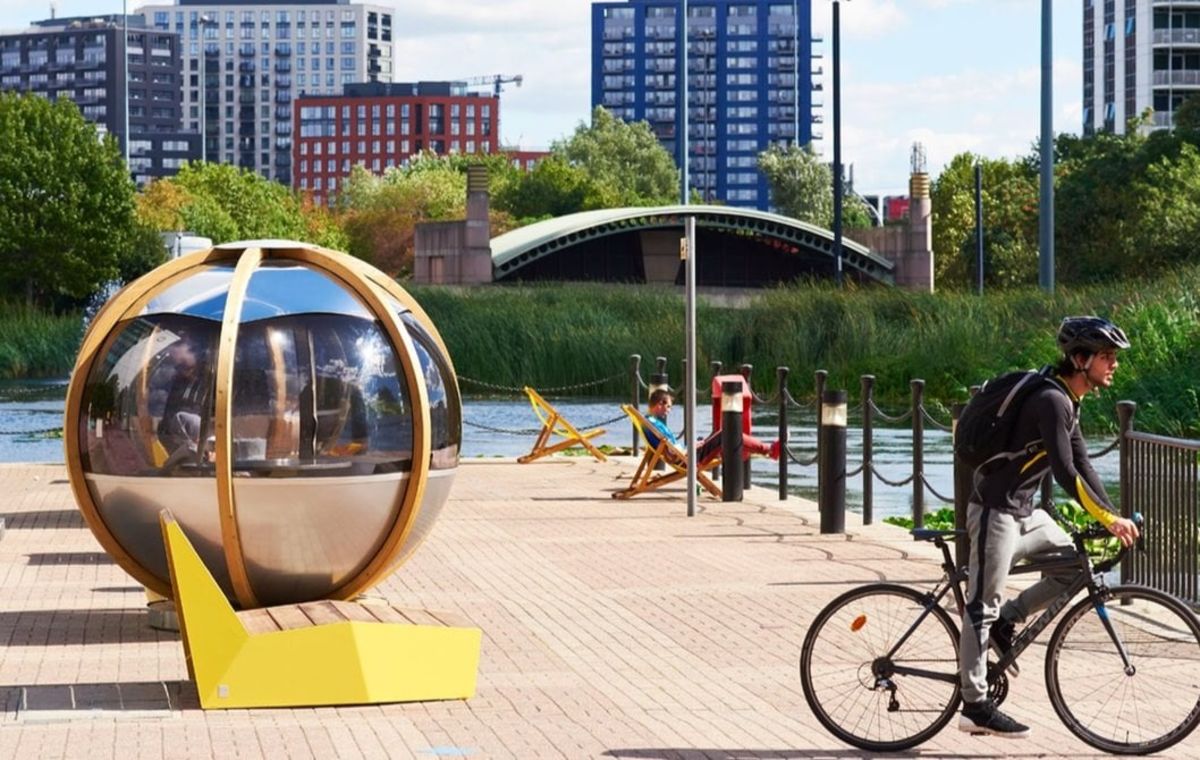A cyclist passes a modern spherical structure on Clove Crescent in London.