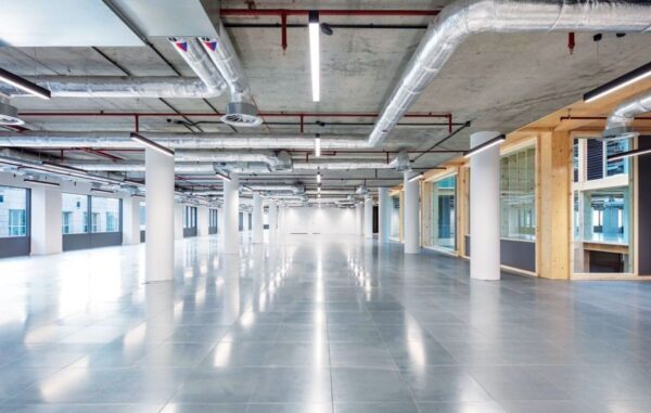 Spacious, modern office interior with exposed ductwork and large windows at Clove Crescent 2, London.