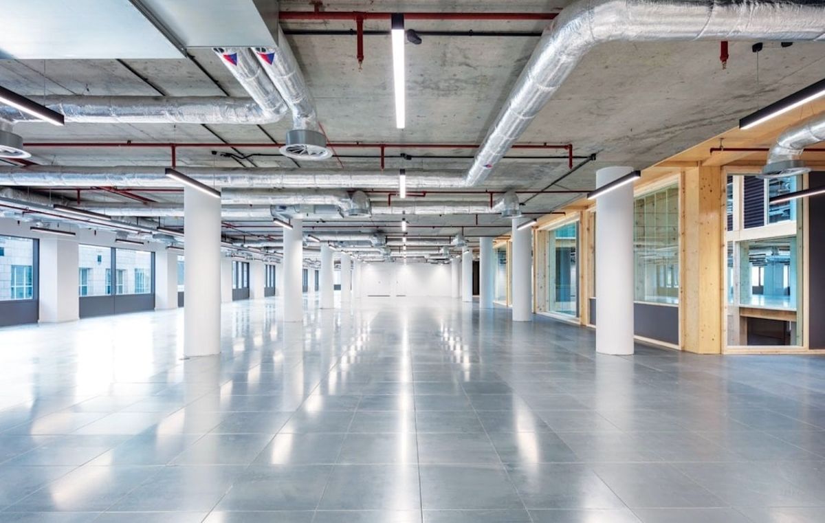 Spacious, modern office interior with exposed ductwork and large windows at Clove Crescent 2, London.