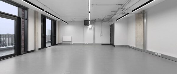 Empty modern office space with large windows and industrial lighting in Corsican Square 7, London.