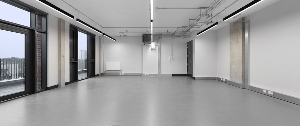 Empty modern office space with large windows and industrial lighting in Corsican Square 7, London.