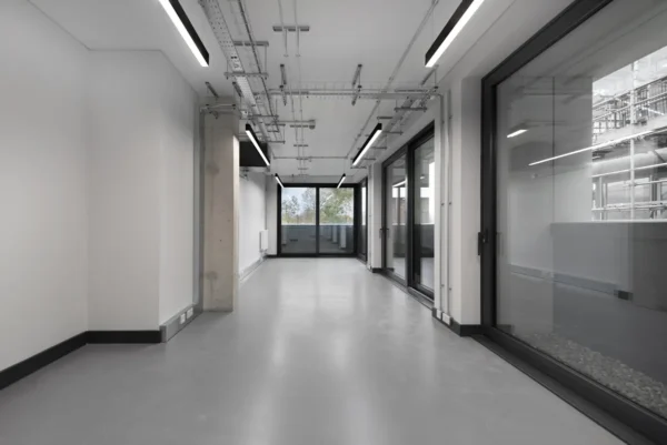 Empty modern office space in Corsican Square, London, with glass doors and exposed ceiling fixtures.
