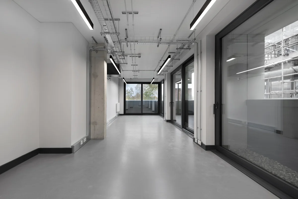 Empty modern office space in Corsican Square, London, with glass doors and exposed ceiling fixtures.