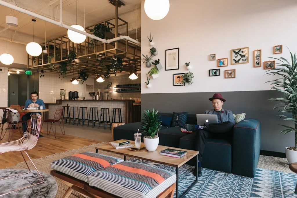A modern lounge area in Devonshire Square 10, London, featuring seating, plants, a laptop user, and artistic wall decor.