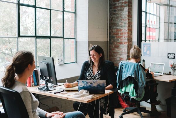 Three people working and chatting in a bright, modern office space.