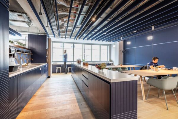 Modern office kitchen and dining area with blue cabinetry and ceiling accents at Folgate Street 35-41, London.