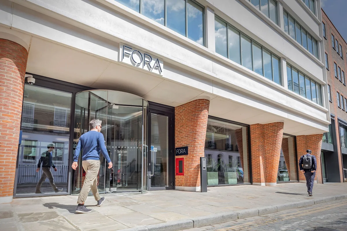 Two people walking outside the Fora building on Folgate Street, London.