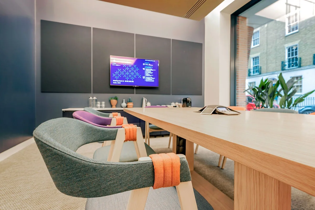 A modern conference room with colorful chairs and a large wooden table.