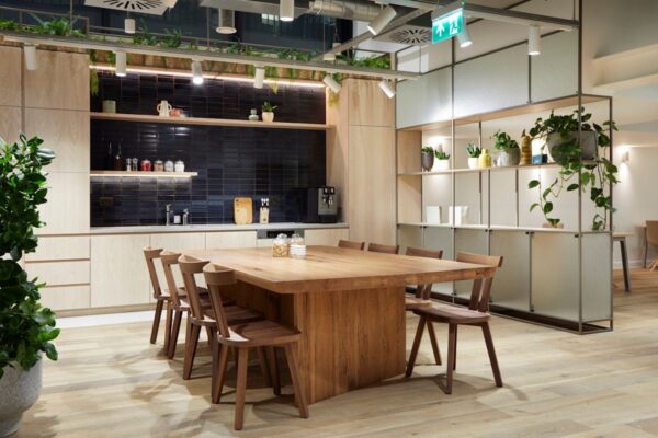 Modern kitchen and dining area with a wooden table and chairs, surrounded by plants and ambient lighting.