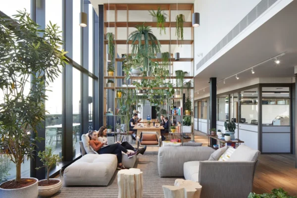 Modern office lounge area with abundant plants, natural lighting, and people working on laptops at Great Eastern Street 21-33, London.