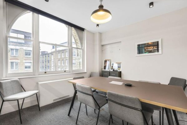 A modern meeting room in Great Eastern Street 40, London, featuring a large table, chairs, and a window with an urban view.