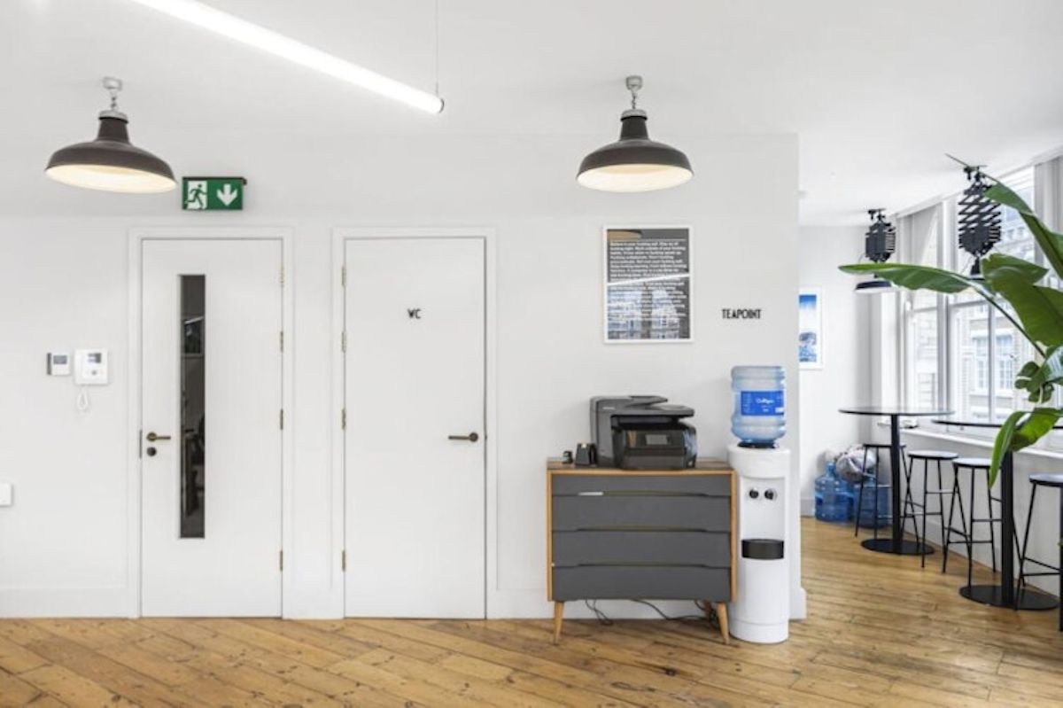 A modern office space on Great Eastern Street 40 in London with a water cooler, printer, and high tables.