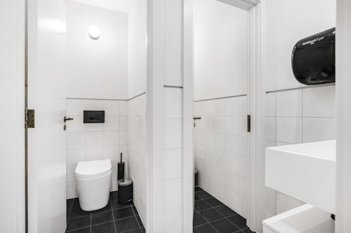 A modern restroom with white tiles and black flooring at 40 Great Eastern Street, London.