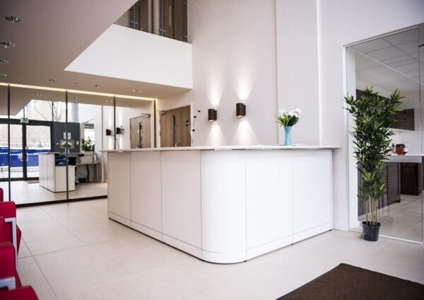 Modern reception area in Indescon Square 5, London, featuring a sleek white desk and contemporary decor.