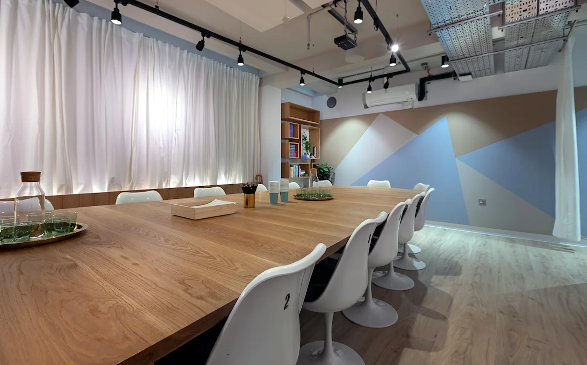 A modern conference room in Ingestre Place, London with a large wooden table and white chairs.