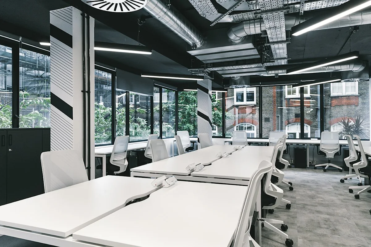 Modern office space at Ingestre Place, London, featuring sleek white desks and chairs with large windows.