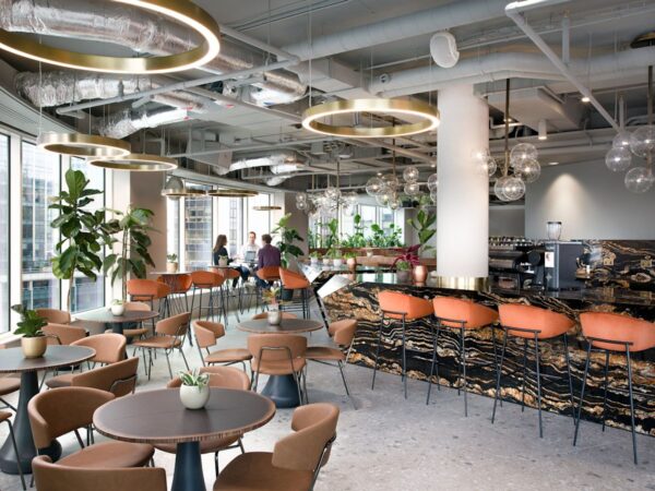 A modern office cafe with stylish seating, large windows, and indoor plants at Liverpool Street, London.