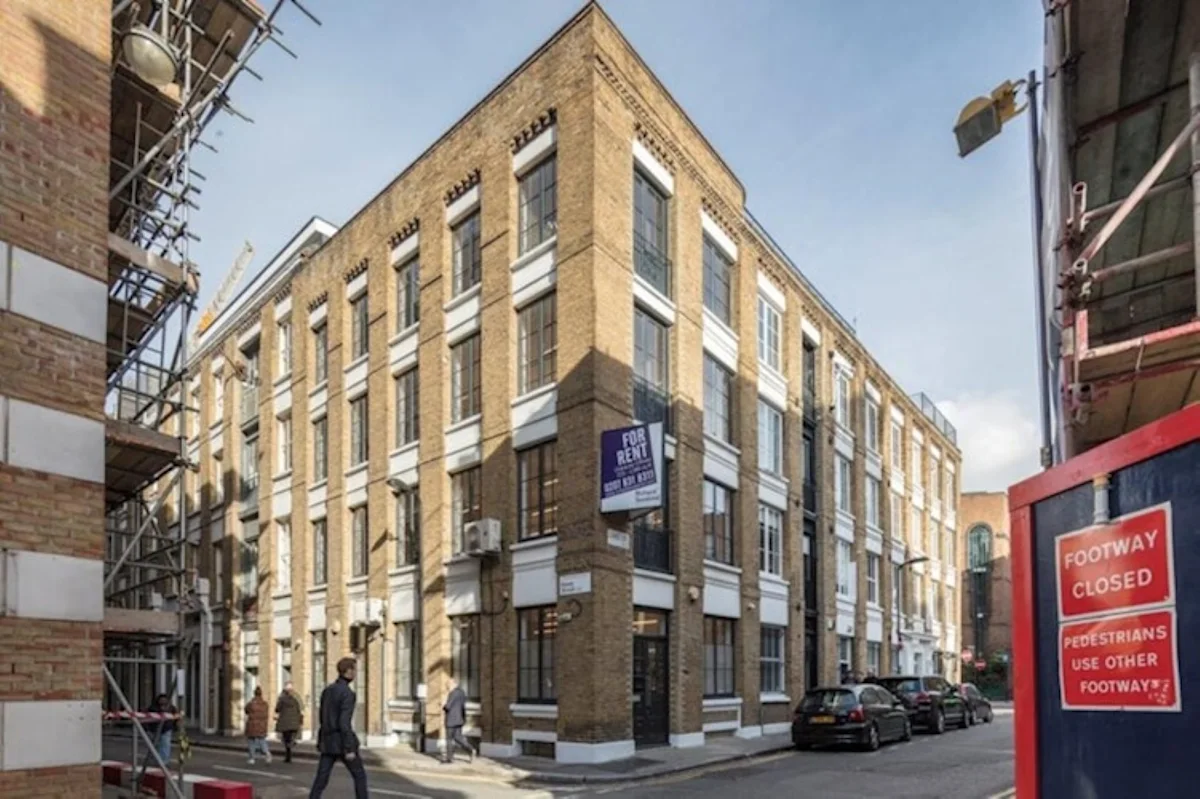 A corner building with a "For Rent" sign on Luke Street 78a, London, surrounded by scaffolding and a "Footway Closed" sign.