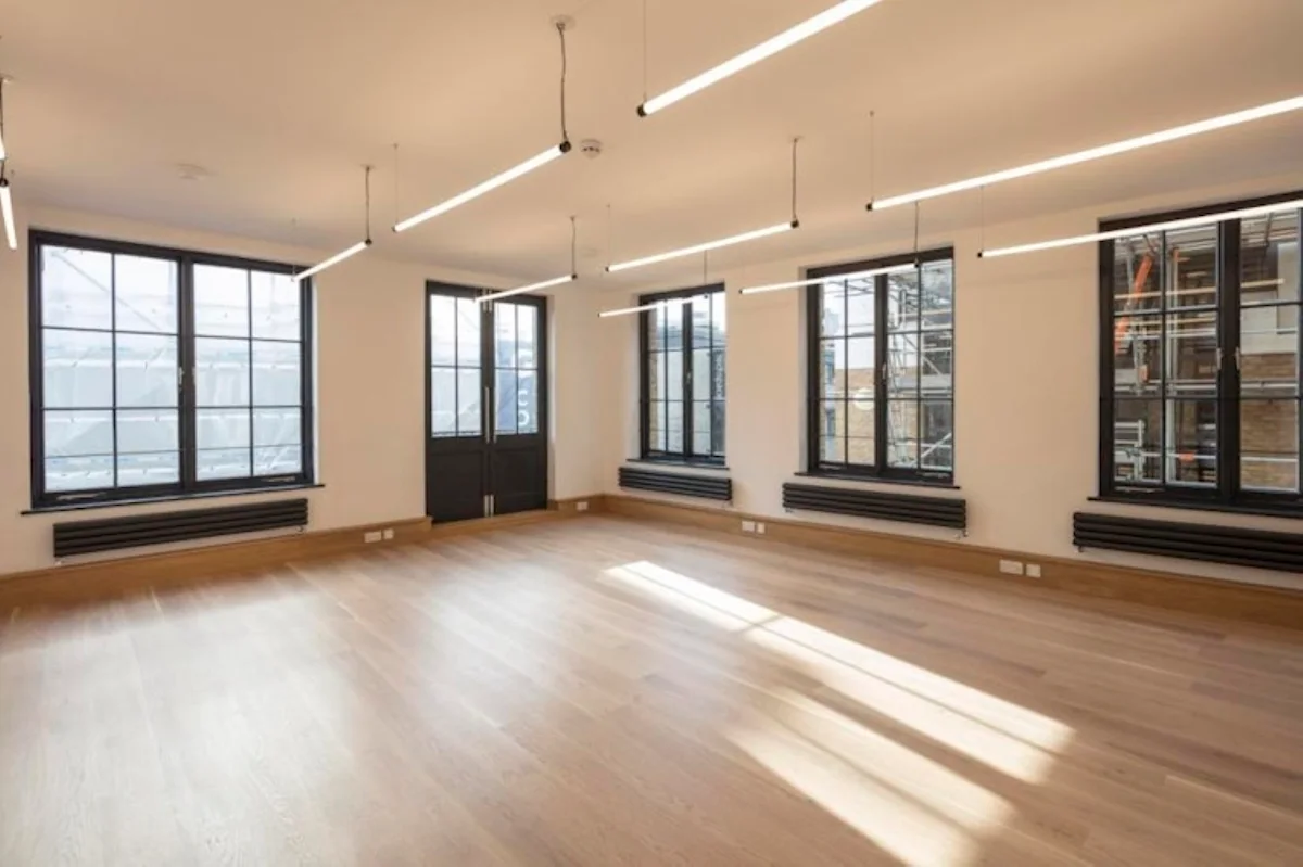 Spacious, modern interior of an empty room with large windows and wooden flooring at Luke Street 78a, London.