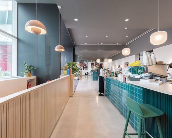 A modern café interior at Marsh Wall 77, London, featuring a sleek design with blue-tiled countertops and hanging lamps.