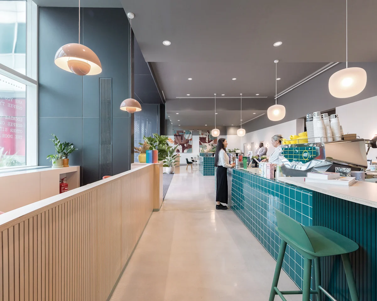 A modern café interior at Marsh Wall 77 in London with teal tiled counters and pendant lights.