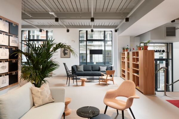 A modern, well-lit office lounge featuring cozy seating, indoor plants, and wooden shelving at New Broad Street 35, London.