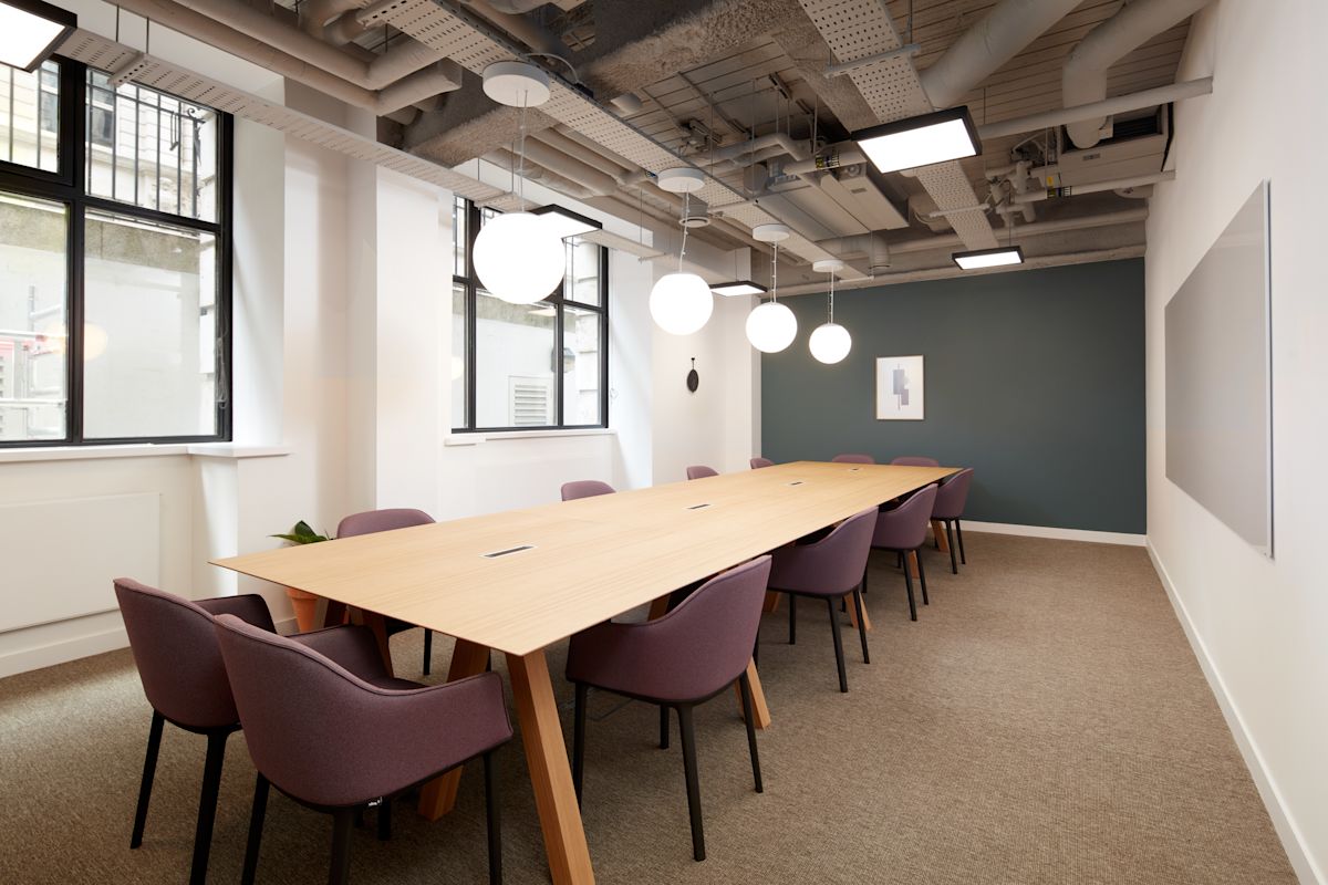 A modern conference room with a long wooden table and purple chairs at New Broad Street 35, London.