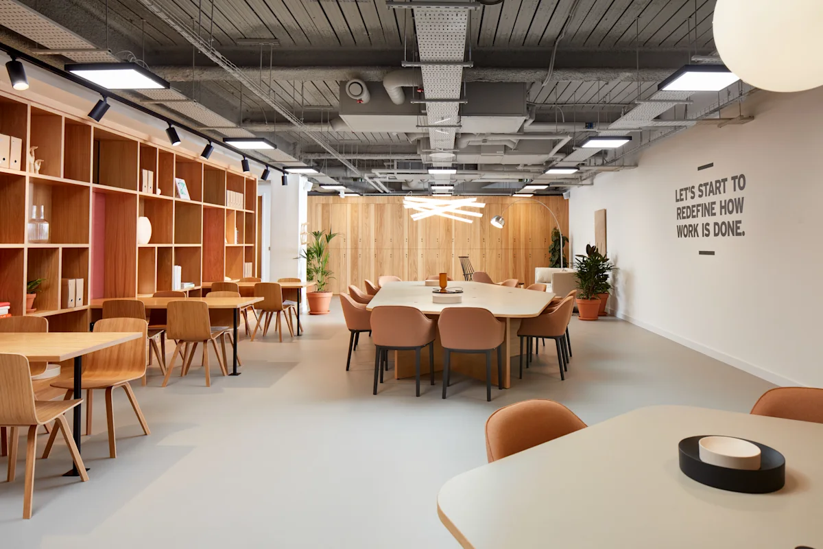 Modern office space with wooden furniture and wall slogan at New Broad Street 35, London.