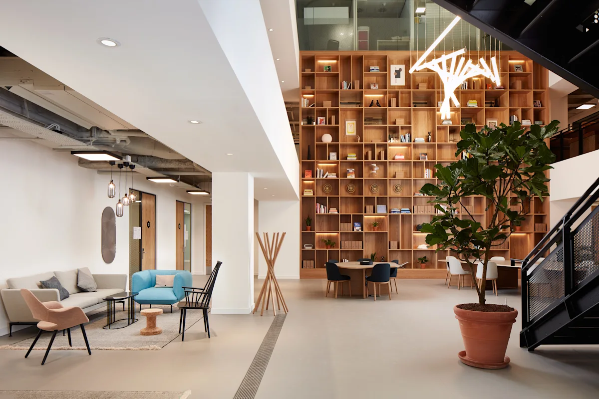Modern office lobby at New Broad Street 35, London, featuring stylish furniture, a large bookshelf, and a contemporary light fixture.