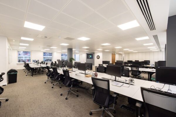 A modern, empty office space with rows of desks and computers at 42 New Broad Street, London.