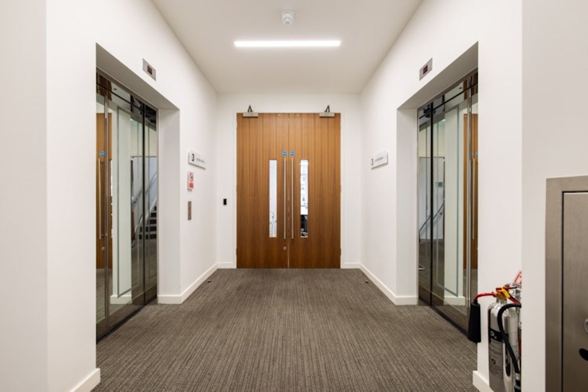 Hallway with two elevators and a wooden double door at New Broad Street 42, London.