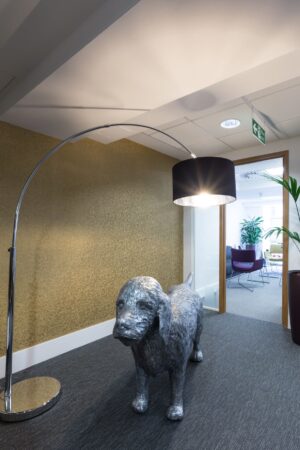 A modern office hallway features a large dog sculpture and an arc floor lamp.