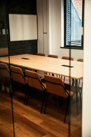 A modern conference room with a large wooden table and brown chairs.