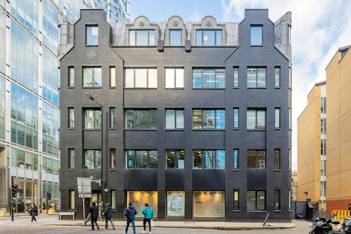 A modern black brick building on Norton Folgate in London, surrounded by glass and brick structures.
