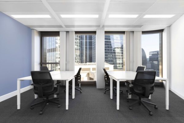 A modern office space with desks and chairs, featuring large windows overlooking the city skyline.