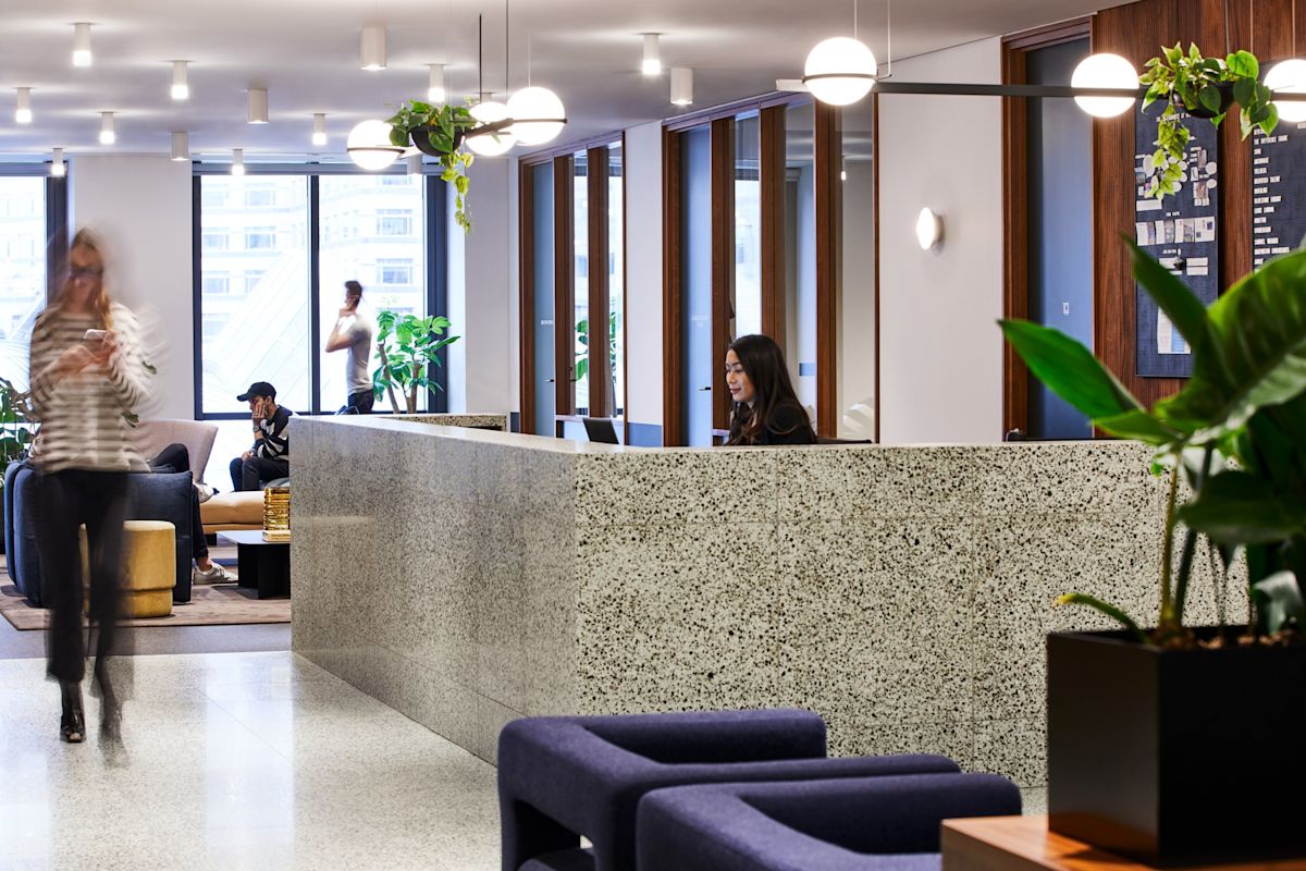 Modern office reception area with people and a receptionist at One Canada Square, London.
