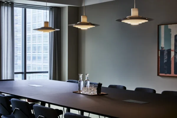 A modern conference room with a large table, elegant lighting, and a view of One Canada Square through the window.