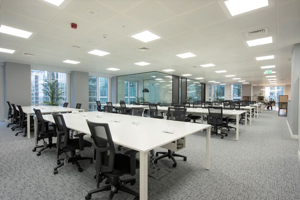 Modern office space with rows of desks and chairs inside One Canada Square, London.