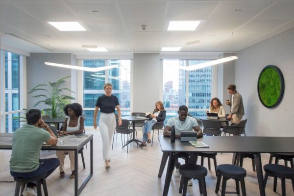 A modern office space in One Canada Square with people working and collaborating around tables.