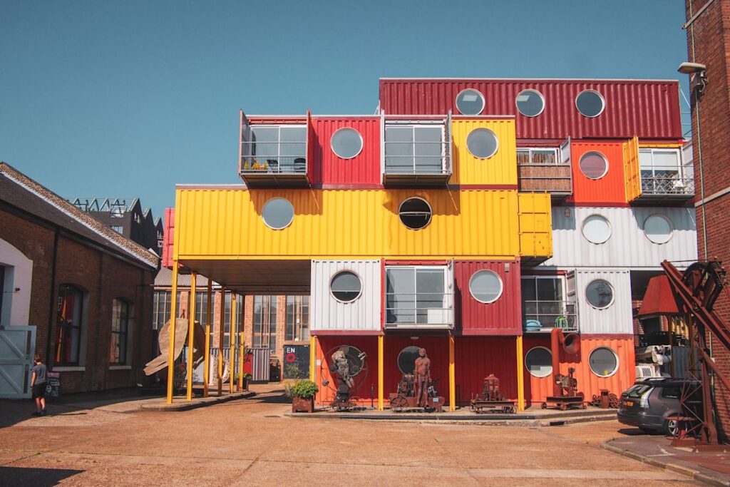 A colorful building made from stacked shipping containers with round windows at Orchard Place 64 in London.