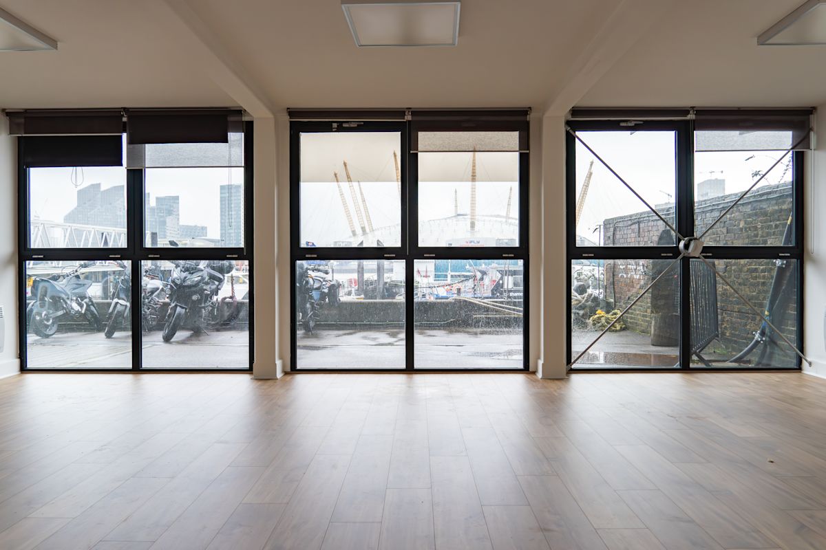 View through large windows overlooking Orchard Place 64 in London, featuring parked motorcycles and the O2 Arena in the background.