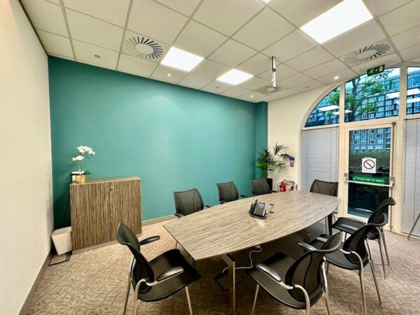 A modern conference room at Pepper Street 16, London, featuring a large oval table and several chairs.