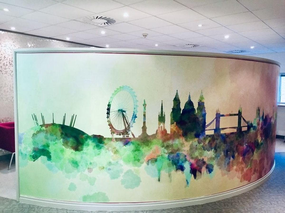A curved wall with a colorful watercolor mural of London's skyline.