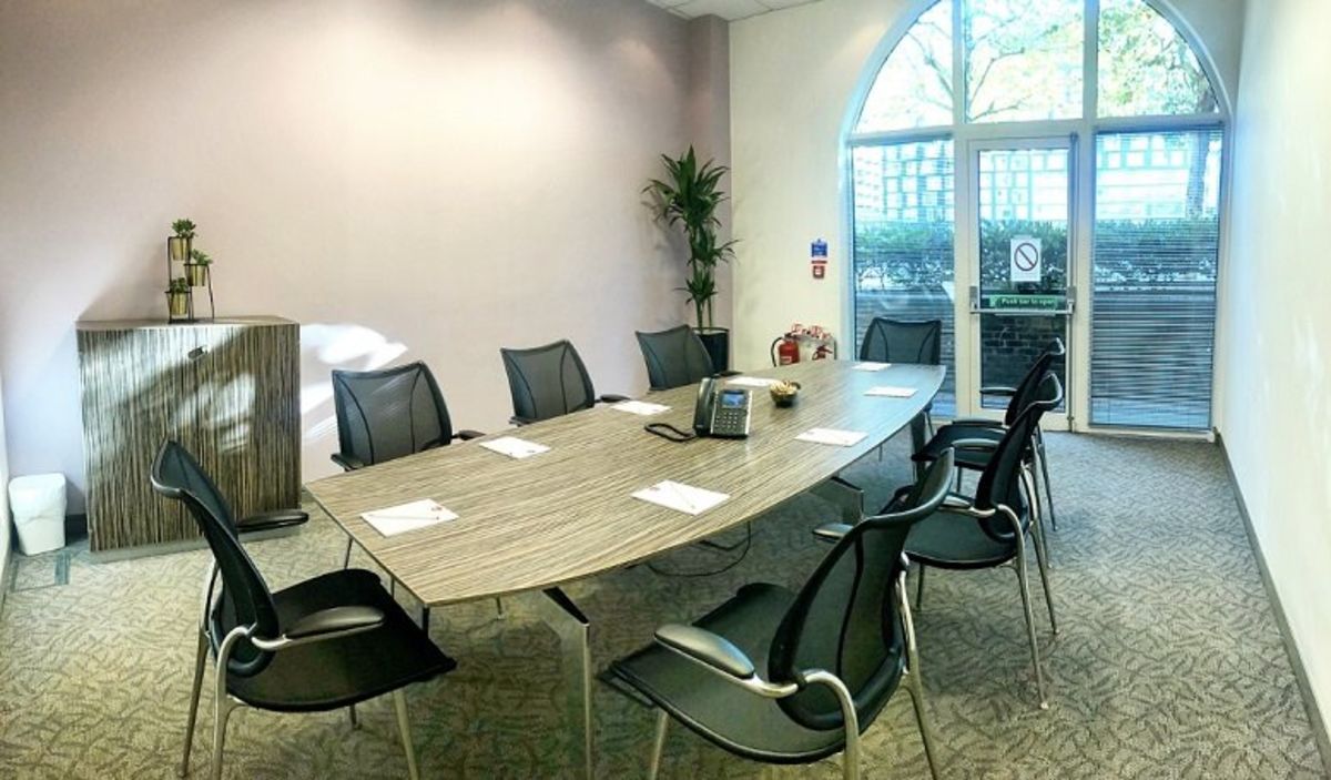 A modern conference room with a long table, black chairs, and a large window at Pepper Street 16, London.