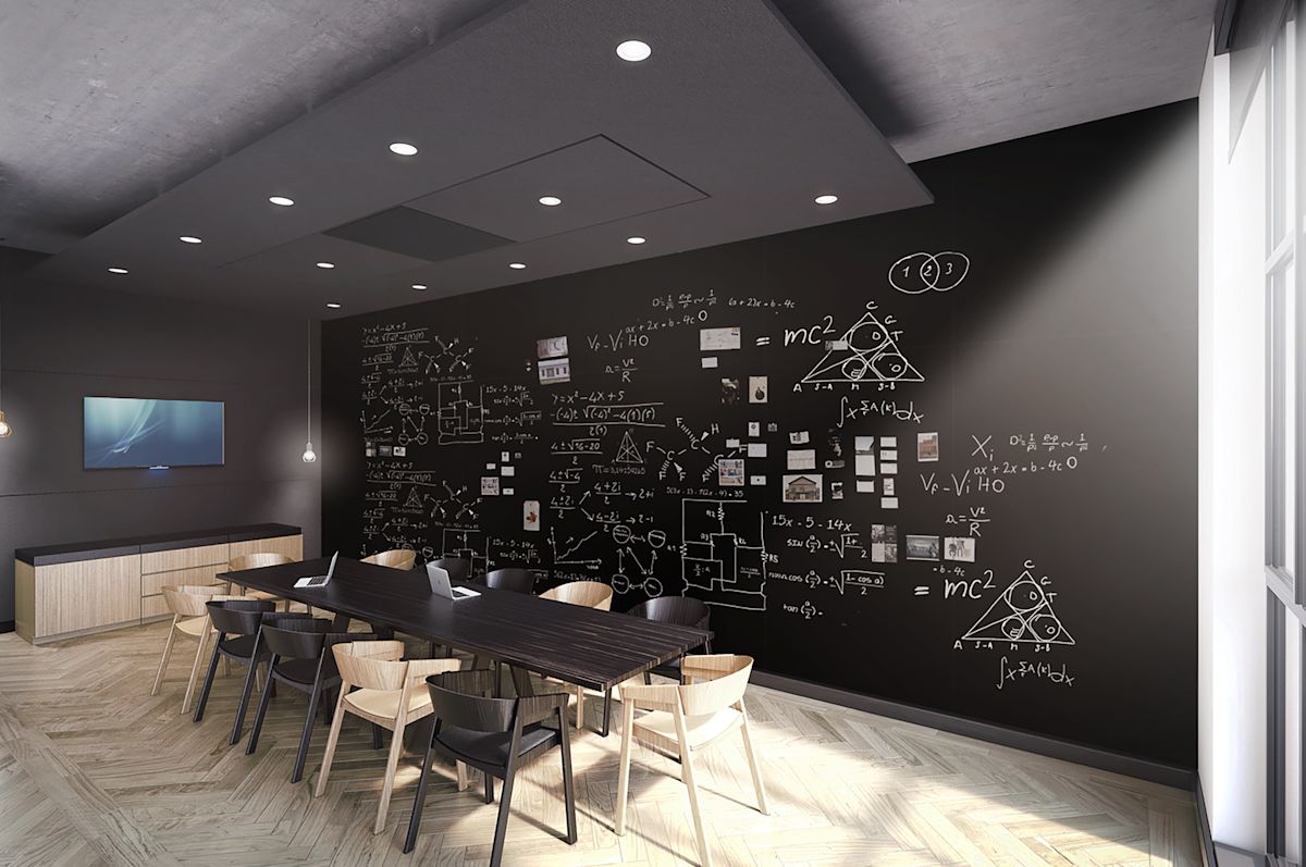 A modern meeting room with a blackboard wall covered in scientific equations and diagrams.