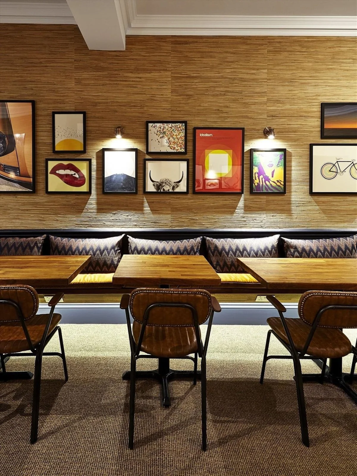 A cozy dining area with wooden tables, chairs, and a wall adorned with eclectic artwork.