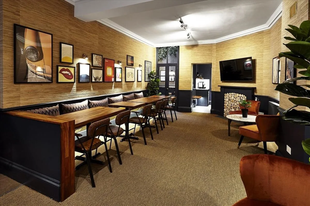 A cozy, stylishly decorated room in Poland Street 54, London, featuring a long wooden table, several chairs, and art-filled walls.