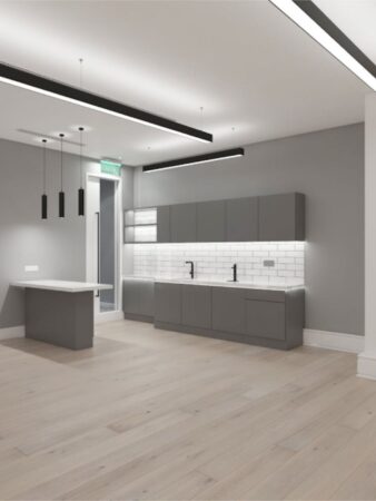 A modern, minimalist kitchen interior with gray cabinets and light wood flooring at Poland Street 6, London.