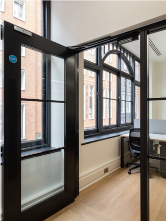 Modern office space with large windows and wooden floors on Poland Street, London.